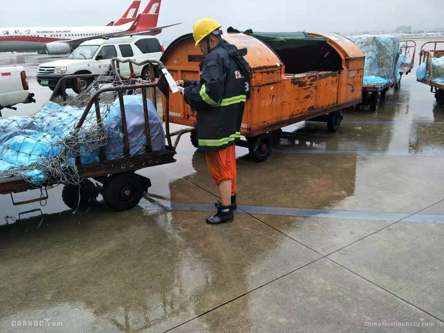 東航虹橋裝卸服務(wù)中心員工正在風(fēng)雨中核對拖車中裝載的行李和貨物清單。供圖/東航